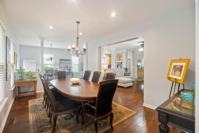 dining room featuring ornate columns, ceiling fan with notable chandelier, and dark hardwood / wood-style flooring