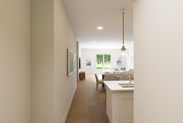 hallway featuring baseboards, dark wood-style flooring, a sink, and recessed lighting