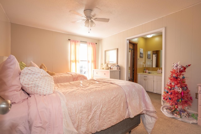 bedroom featuring ceiling fan, carpet floors, a textured ceiling, and ensuite bath