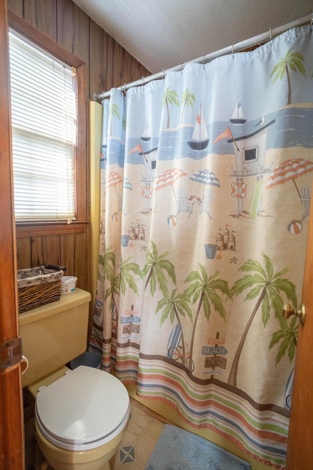 bathroom with wooden walls, toilet, and a shower with shower curtain