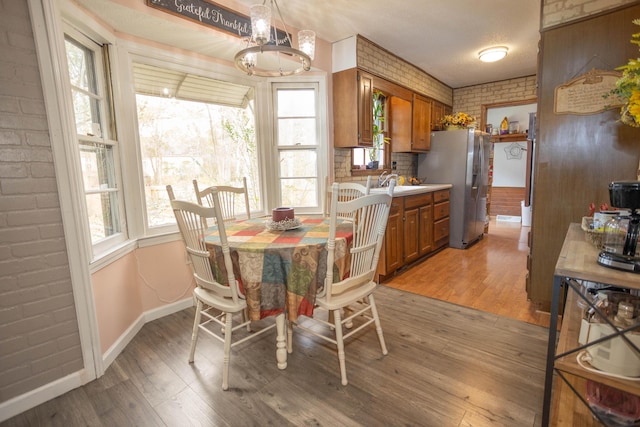 dining area with hardwood / wood-style flooring, brick wall, and sink