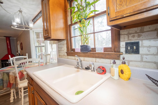 kitchen featuring sink, a notable chandelier, hanging light fixtures, and a wood stove