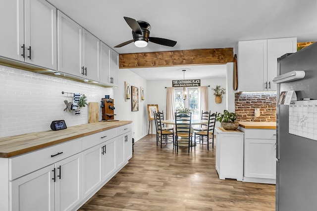 kitchen featuring white cabinets, a ceiling fan, decorative backsplash, wood finished floors, and butcher block counters