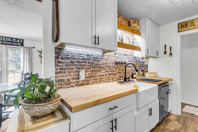 kitchen with open shelves, a sink, dishwasher, wood finished floors, and butcher block counters