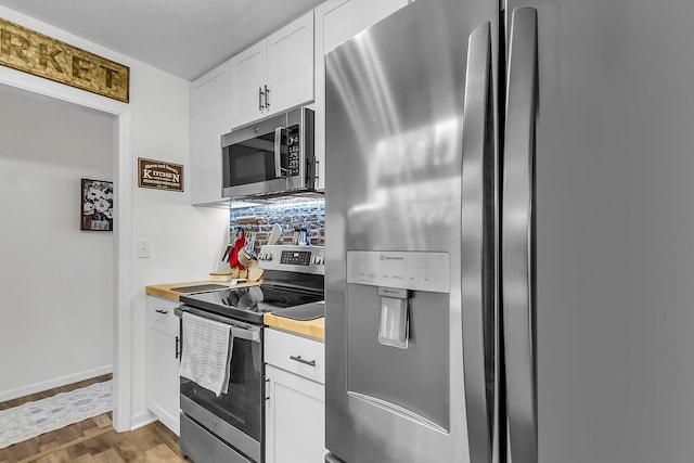kitchen with wood finished floors, baseboards, white cabinets, stainless steel appliances, and butcher block countertops