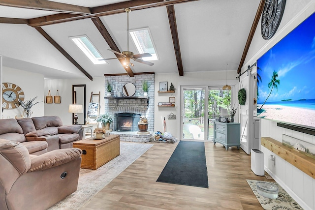 living area with beam ceiling, a fireplace, light wood-style floors, high vaulted ceiling, and a skylight