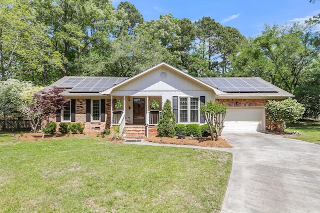 ranch-style house with brick siding, a porch, a front yard, solar panels, and driveway