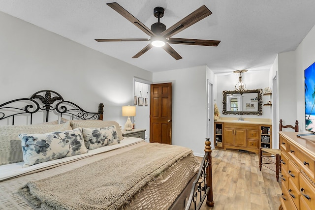 bedroom featuring a ceiling fan, a sink, and light wood-style flooring
