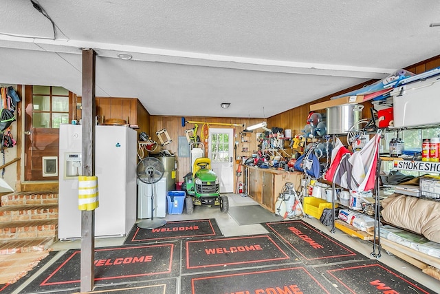 garage featuring wood walls and white refrigerator with ice dispenser