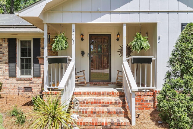 view of exterior entry featuring a porch, solar panels, and brick siding