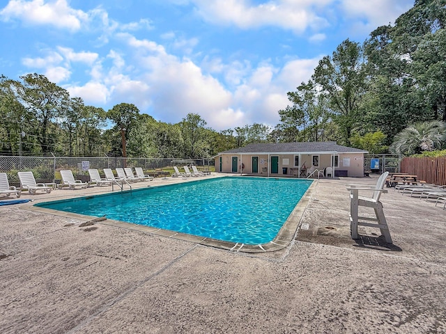 community pool with a patio and fence