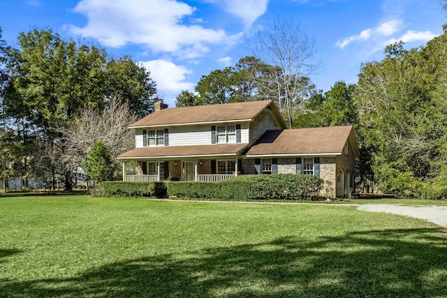 view of front of house featuring a porch, a front lawn, a chimney, and brick siding