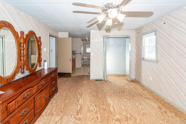 interior space with a paneled ceiling, ceiling fan, light wood-type flooring, and a closet