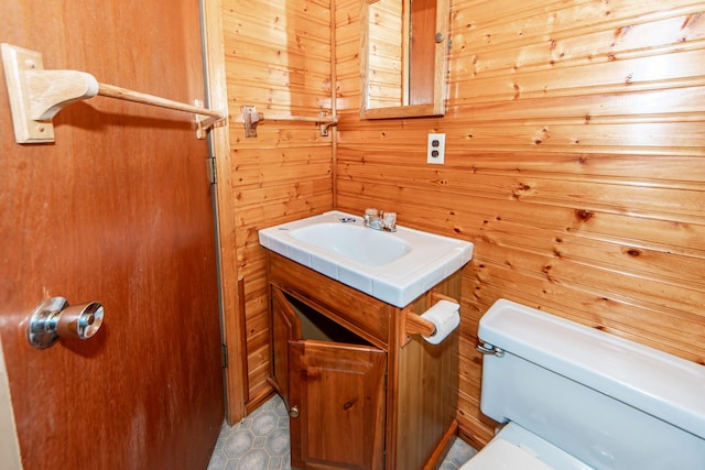 bathroom featuring wooden walls, vanity, and toilet