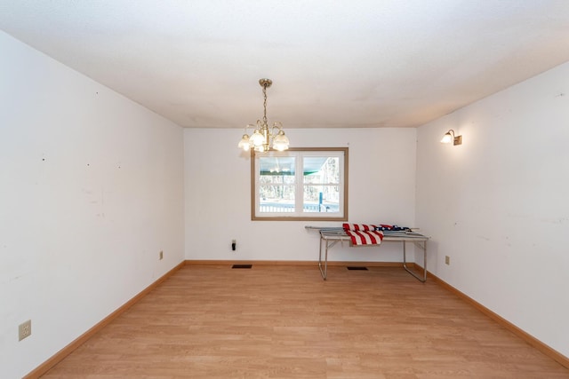 unfurnished dining area with light wood-type flooring and an inviting chandelier