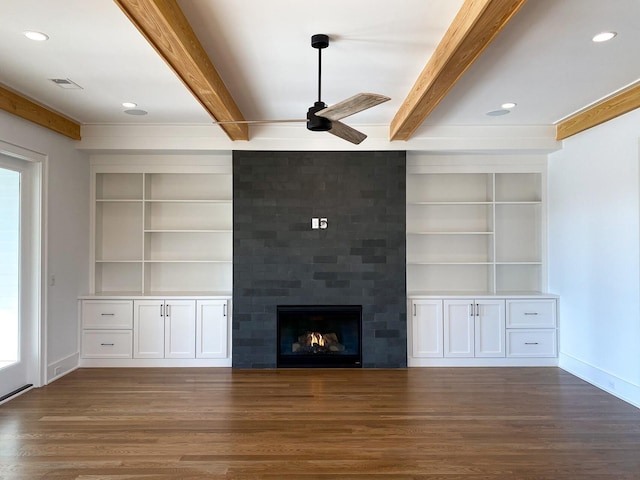 unfurnished living room with wood finished floors, a ceiling fan, beam ceiling, and built in shelves