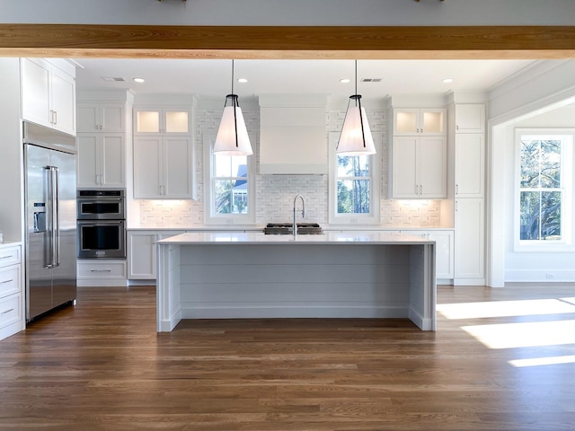 kitchen featuring an island with sink, a sink, appliances with stainless steel finishes, and a healthy amount of sunlight