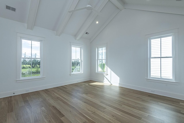 empty room featuring lofted ceiling with beams, a ceiling fan, baseboards, wood finished floors, and visible vents