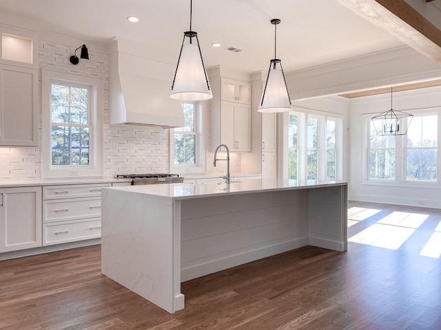 kitchen featuring a sink, wall chimney exhaust hood, backsplash, and white cabinets