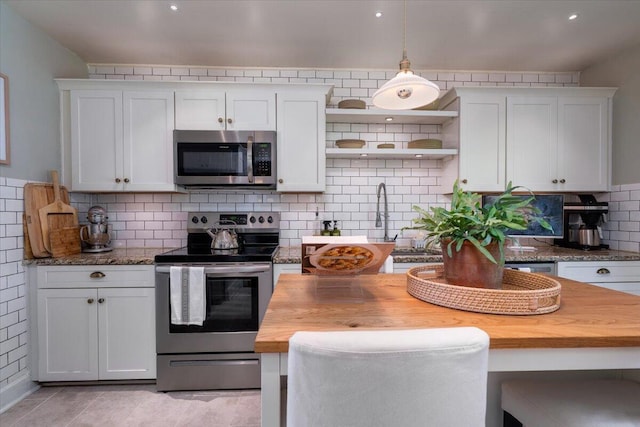 kitchen featuring appliances with stainless steel finishes, white cabinets, and wooden counters