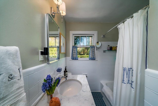 bathroom with a wainscoted wall, shower / bath combo with shower curtain, tile walls, and vanity