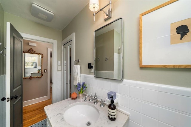 bathroom featuring a wainscoted wall, tile walls, vanity, and wood finished floors