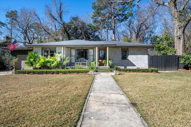 mid-century modern home featuring an attached garage, covered porch, brick siding, fence, and a front yard