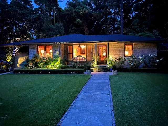 view of front facade featuring brick siding, a porch, and a front yard