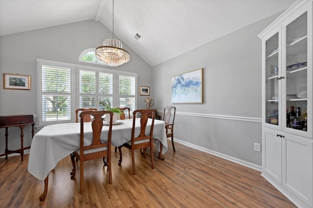 dining area with a chandelier, wood finished floors, high vaulted ceiling, and baseboards