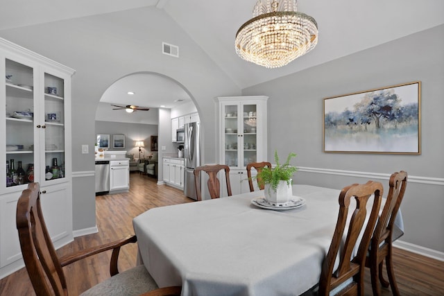 dining area featuring arched walkways, wood finished floors, ceiling fan, a chandelier, and high vaulted ceiling