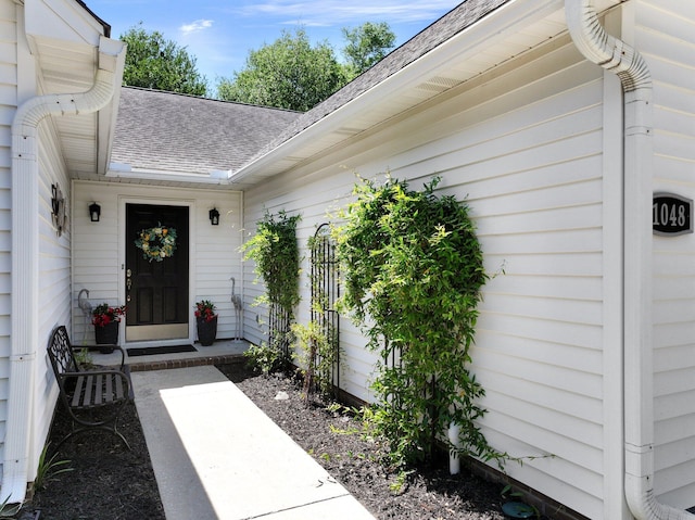 doorway to property with roof with shingles