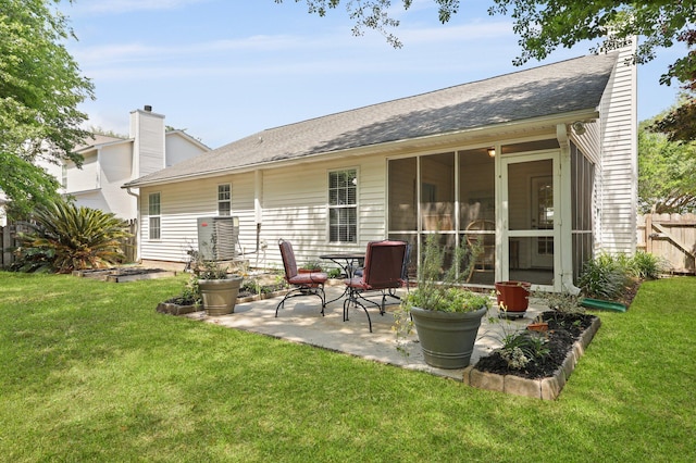 back of house featuring a patio area, a chimney, a shingled roof, and a sunroom