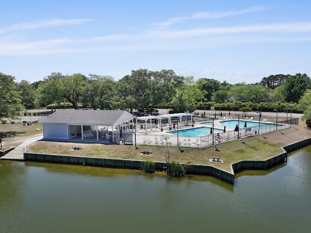 rear view of property with fence, a water view, a community pool, and view of wooded area