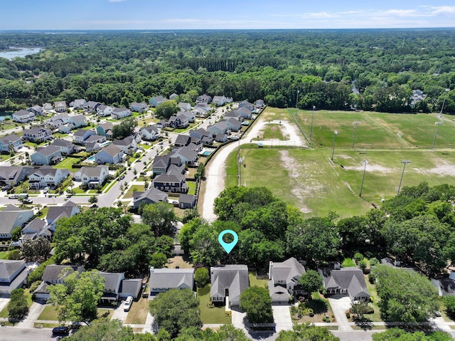 aerial view of property and surrounding area featuring a forest and nearby suburban area