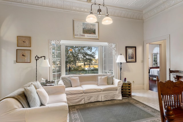 living room with crown molding, a chandelier, tile floors, and a high ceiling