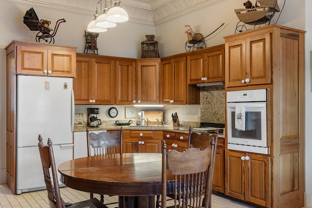 kitchen featuring decorative light fixtures, white appliances, light stone counters, and light tile flooring