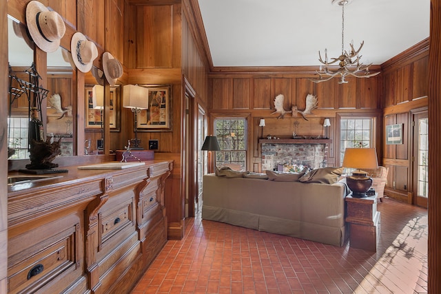 living room featuring wooden walls, a notable chandelier, and ornamental molding