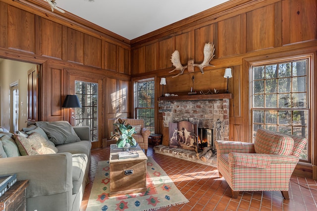 living room featuring crown molding, a fireplace, wood walls, and dark tile floors