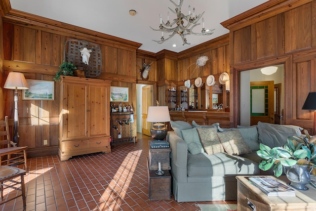 living room featuring an inviting chandelier, ornamental molding, and wooden walls