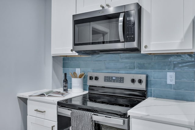 kitchen featuring stainless steel appliances, white cabinets, light stone counters, and decorative backsplash