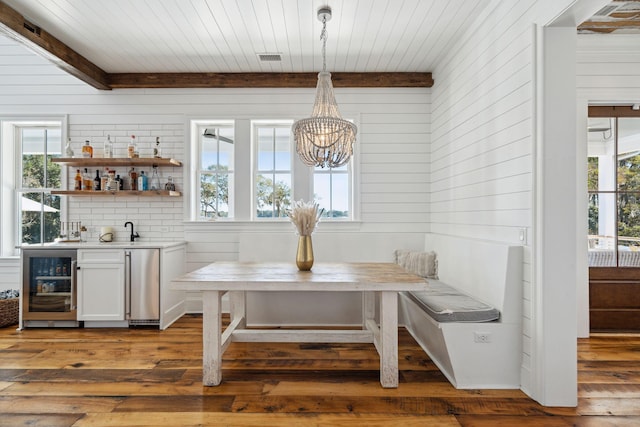 dining room with a notable chandelier, dark wood-type flooring, a healthy amount of sunlight, and beverage cooler