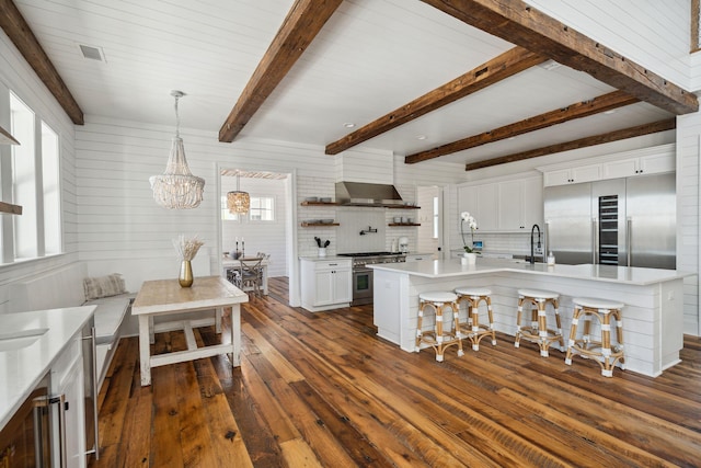 kitchen with decorative light fixtures, high quality appliances, tasteful backsplash, a breakfast bar area, and white cabinetry