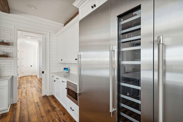 kitchen featuring white cabinets, wall oven, built in fridge, and dark hardwood / wood-style flooring