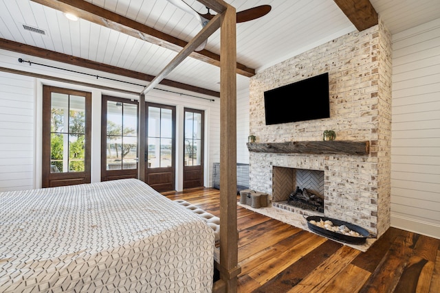 bedroom featuring a brick fireplace, vaulted ceiling with beams, and dark hardwood / wood-style flooring