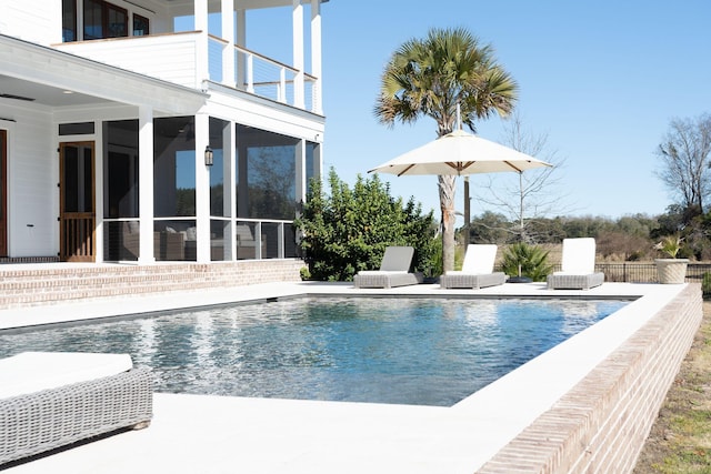 view of swimming pool featuring a sunroom and a patio area