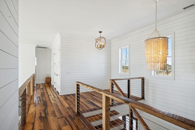 corridor with wooden walls, dark hardwood / wood-style floors, and a chandelier