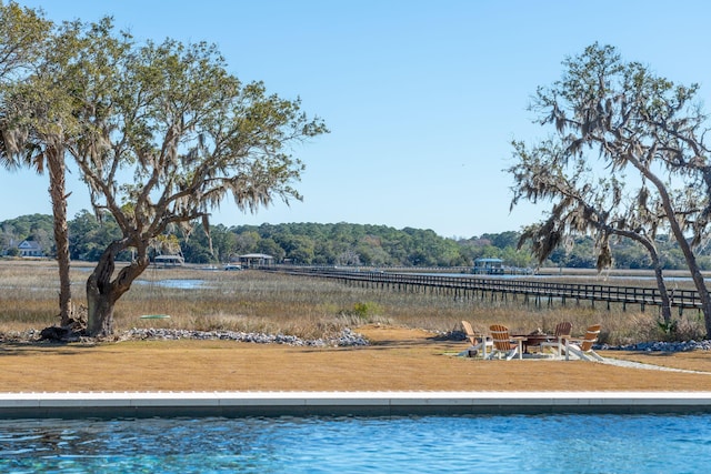 view of pool with a water view and a lawn