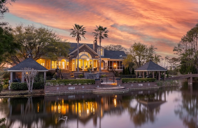 back house at dusk featuring a water view and a gazebo