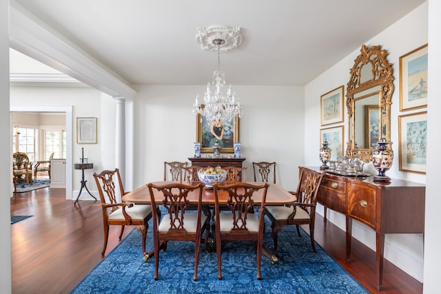 dining area featuring dark hardwood / wood-style floors, an inviting chandelier, and decorative columns