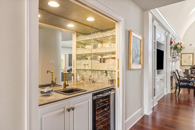 bar featuring wine cooler, sink, dark wood-type flooring, stone counters, and white cabinetry